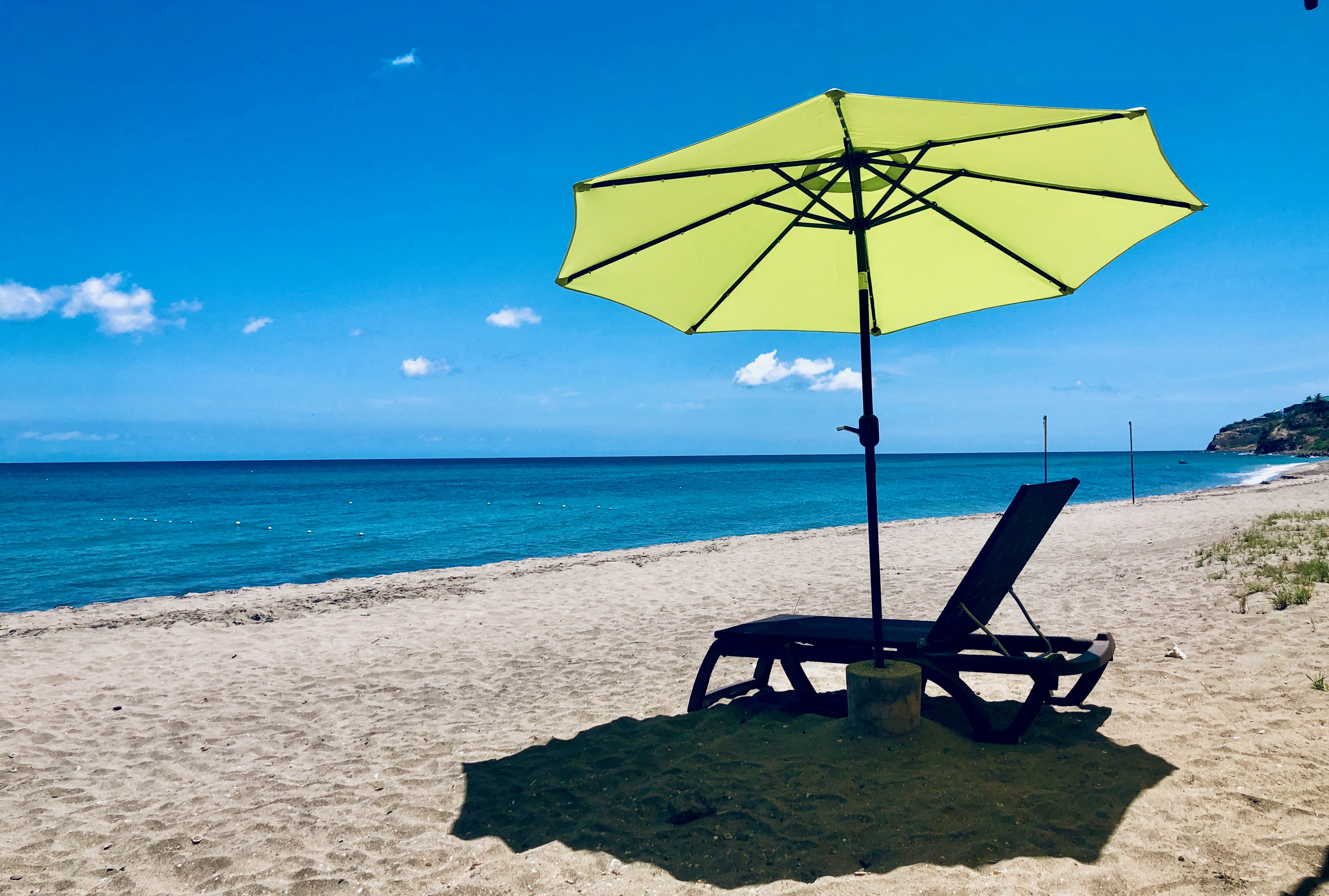 Beach umbrella and lounge chair on white sand